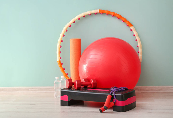 Set of sports equipment with fitness ball near color wall - Photo, Image