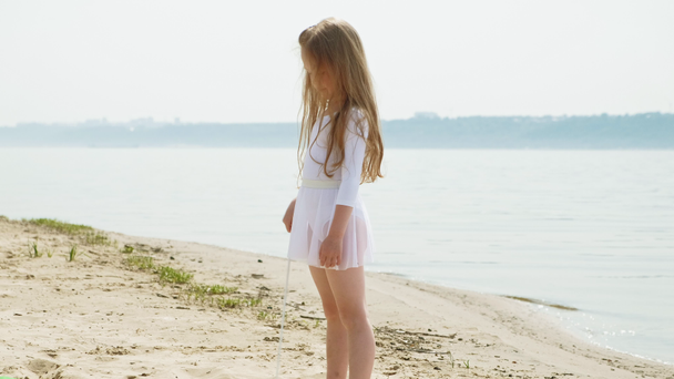  menina pré-escolar com danças uma fita ginástica em uma praia arenosa. Verão, amanhecer
 - Filmagem, Vídeo
