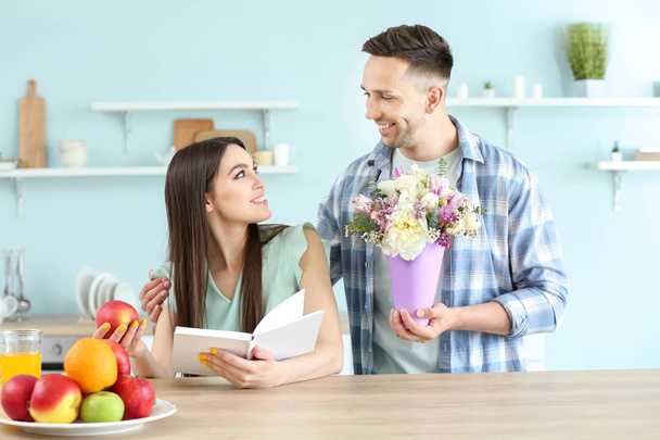 Man groet zijn vrouw met boeket bloemen thuis - Foto, afbeelding