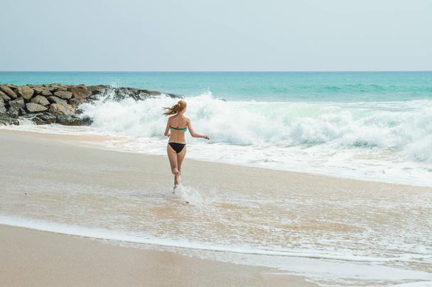 Beautiful young girl running along the beach - Φωτογραφία, εικόνα