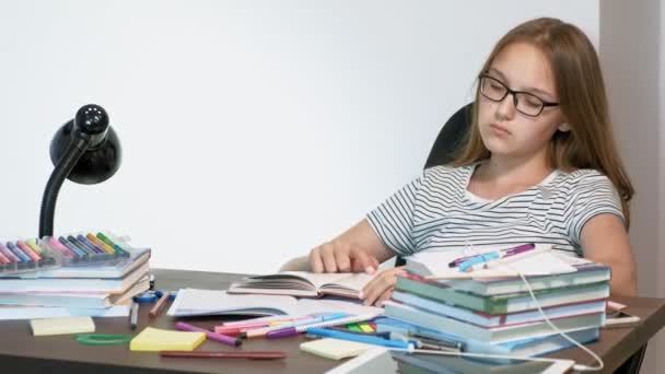 A teenager girl with glasses is sitting at a school desk. learning concept - Záběry, video
