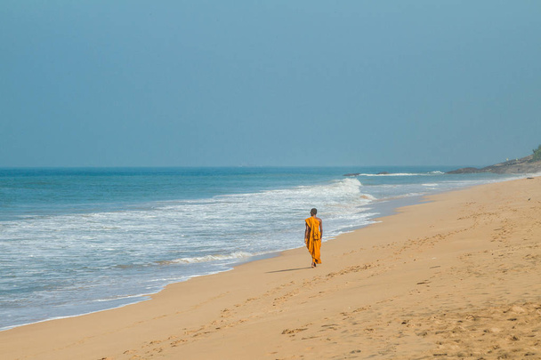 A lone Buddhist monk walks along the ocean shore - Foto, Imagen