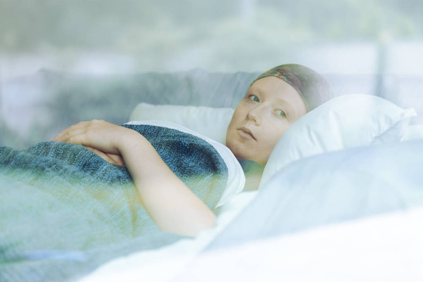 Thoughtful woman battling with tumor lying in hospice bed - Φωτογραφία, εικόνα