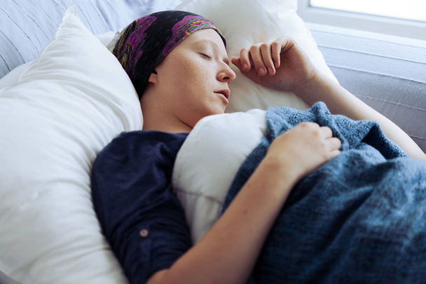Sad cancer suffering girl lying alone in hospital bed - Foto, Bild