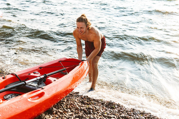 Healthy fit man on a kayak in the ocean - Foto, imagen