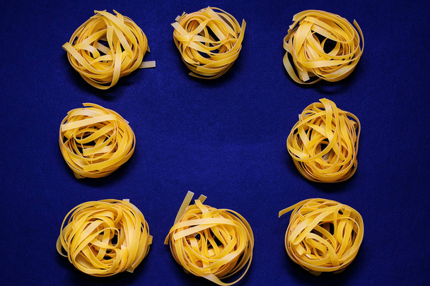Dry pasta yellow on a dark background. Italian food - Φωτογραφία, εικόνα