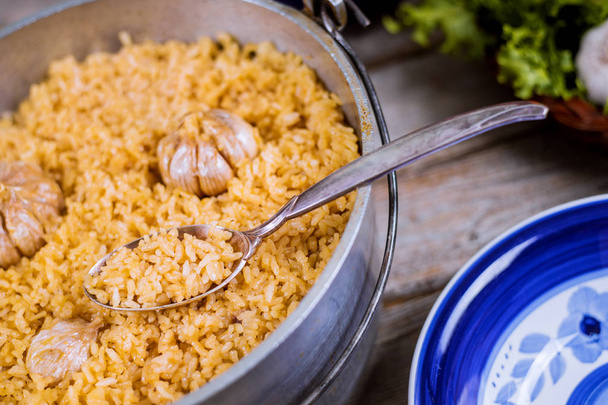 Özbek pilavı, demir tencere ve tabakta sarımsaklı pirinç. - Fotoğraf, Görsel