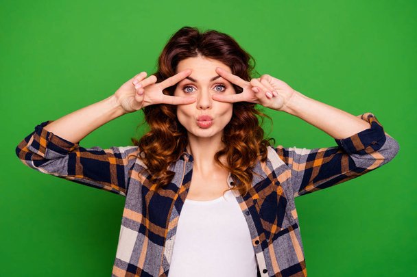 Close-up portrait of her she nice lovely lovable sweet attractive cheerful positive wavy-haired girl in checked shirt showing double v-sign near eyes isolated on bright vivid shine green background - Foto, imagen