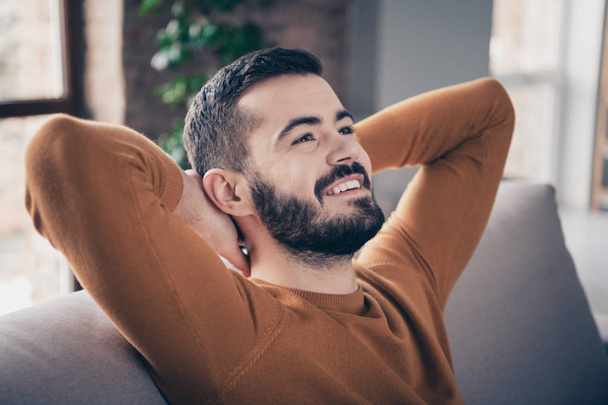 Close-up portrait of his he nice-looking attractive bearded cheerful cheery confident guy sitting on divan spending spare time at industrial loft interior style living-room indoors - Фото, зображення