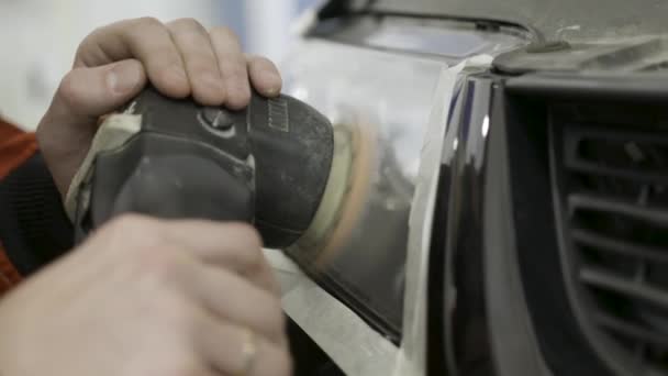 Close up for auto mechanic buffing and polishing car head. light. Art. Worker polishing the headlight of a car at automobile repair and renew service station, using a professional power buffer machine - Footage, Video