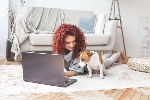 Young attractive woman playing with her little cute dog. Female training her pet indoors.  - Fotoğraf, Görsel