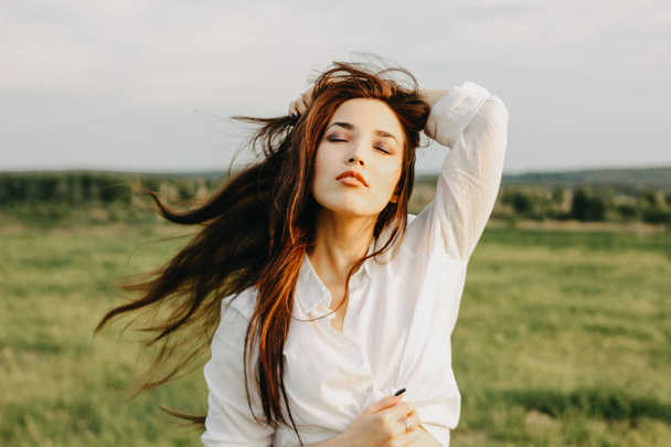 Portret pięknej beztroskie długie włosy dziewczyna w białych ubrań na polu o zachodzie słońca. Wrażliwość na pojęcie natury - Zdjęcie, obraz