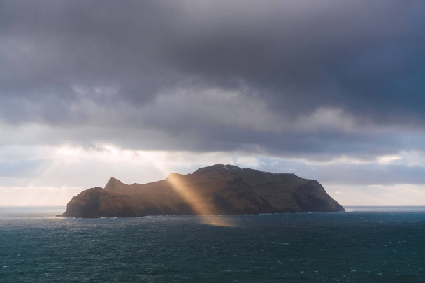 Sun shining through clouds near cliff - Foto, imagen