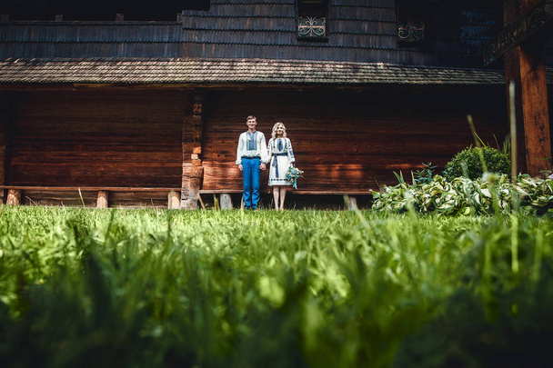 Niesamowita para ślubna w koszulce z haftem z grono kwiatów na tle drewnianego domu - Zdjęcie, obraz