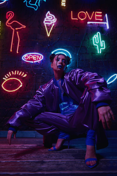 cyberpunk shooting of model wearing contemporary sportswear against wall of neon - Foto, imagen