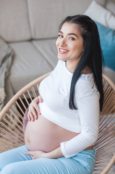 Una joven atractiva esperando un hijo. Una mujer embarazada. Mujer en el interior abrazando su estómago
. - Foto, Imagen