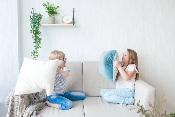 Cute little kids playing with pillows indoors. Brother and sister having fun together. Pillow fight. - Photo, Image