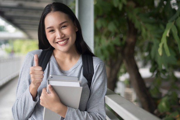aasialainen nainen opiskelija osoittaa peukalo ylös ele; hyväksyminen, hyväksyminen, hyvä, kyllä, ok käsite
 - Valokuva, kuva