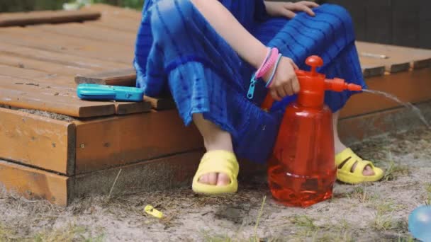 Маленькая девочка наливает воду в водяной шар в теплый летний день
 - Кадры, видео