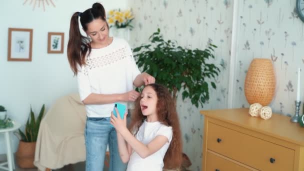 Mother combs and braids hair of daughter in pigtail, slow motion - Кадри, відео