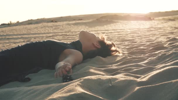 Vrouw liggend op het zand bij zonsondergang - Video