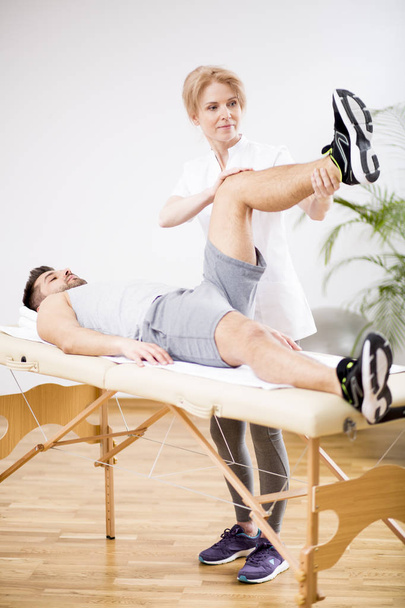 Handsome young man during physiotherapy session with professional doctor - Foto, afbeelding