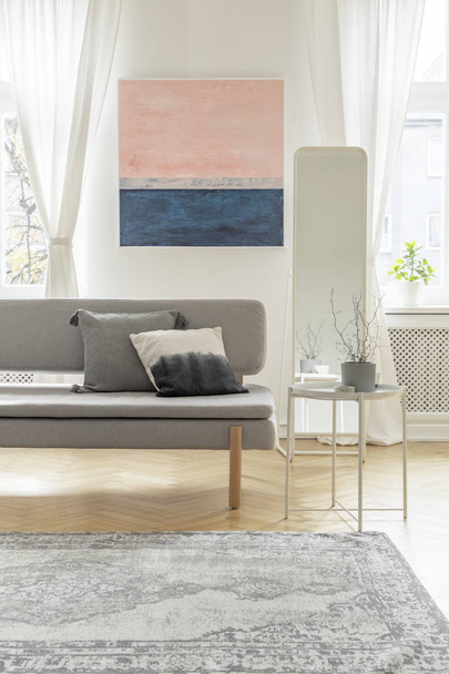 Fashionable settee with pillows in bright living room interior with pastel pink and blue painting - Fotografie, Obrázek