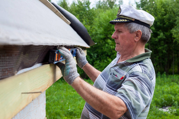 高齢の男性が木造住宅の屋根を建てる - 写真・画像