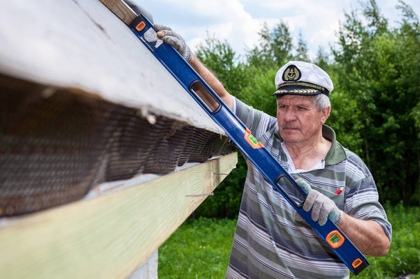 高齢の男性が木造住宅の屋根を建てる - 写真・画像