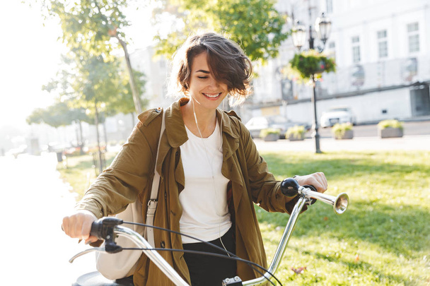 Cute young amazing woman walking outdoors in park with bicycle beautiful spring day. - Zdjęcie, obraz