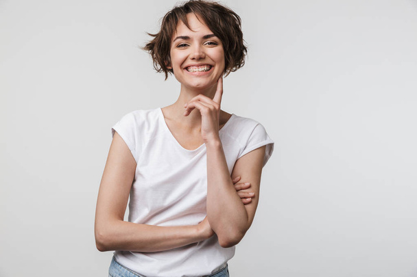 Image of brunette woman in basic t-shirt smiling at camera while - Фото, изображение