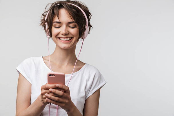 Image of smiling woman in basic t-shirt holding smartphone while - Photo, image
