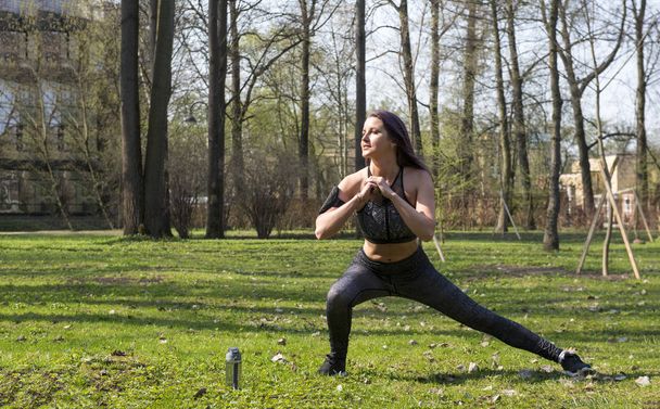 slim girl in sportswear is engaged in fitness in the Park - Foto, Imagem