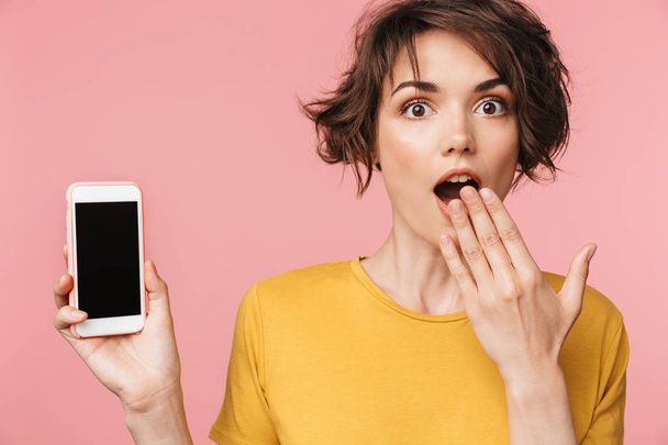 Shocked young beautiful woman posing isolated over pink wall background using mobile phone. - 写真・画像