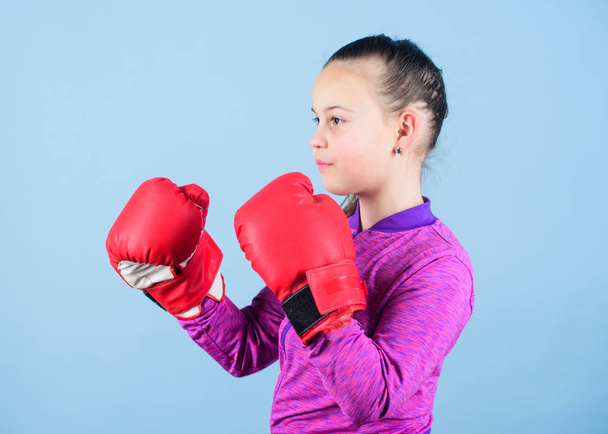 Girl cute boxer on blue background. Contrary to stereotype. Boxer child in boxing gloves. Confident teen. Enjoyment from sport. Female boxer. Sport upbringing. Boxing provide strict discipline - Fotoğraf, Görsel