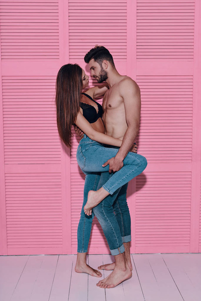 Full length of beautiful young couple bonding face to face while standing against pink background                 - Valokuva, kuva