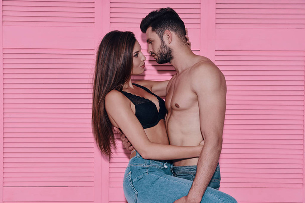 Красивая молодая пара, стоящая лицом к лицу на розовом фоне
 - Фото, изображение