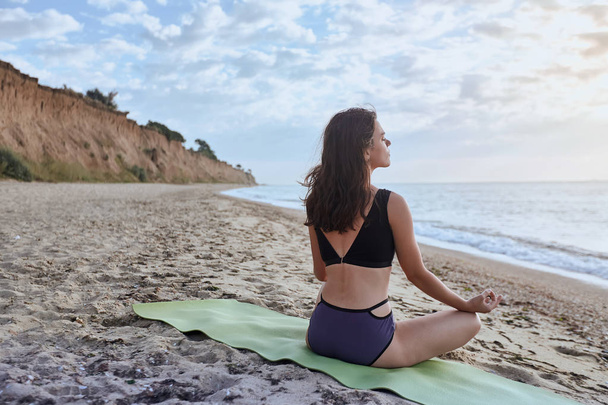 Joyeux jeune femme pratique le yoga et médite en position lotus sur la plage
 - Photo, image