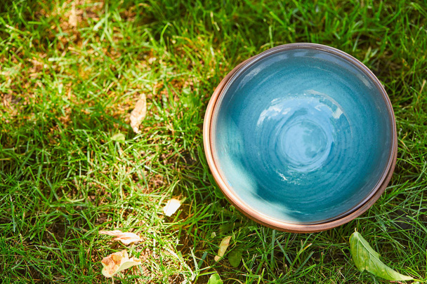 top view of blue ceramic bowl on green grass - Fotó, kép