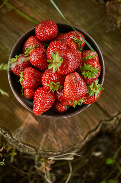 top view of red fresh strawberries in bowl on stump - Фото, зображення