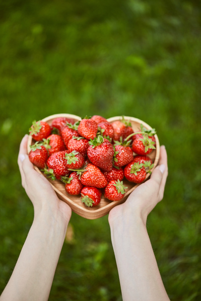 cropped view of woman holding heart shaped plate with strawberries - Photo, Image