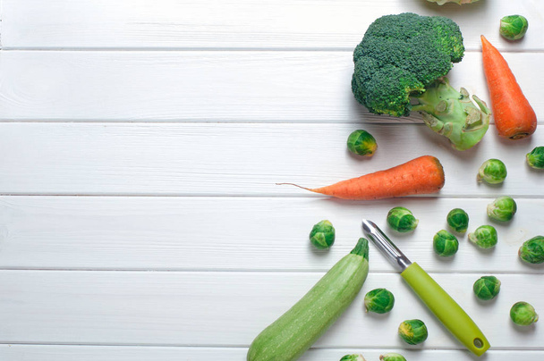 Vegetables and peeler on the white wood background - Φωτογραφία, εικόνα