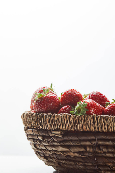 red organic strawberries in wicker basket isolated on white - Фото, изображение