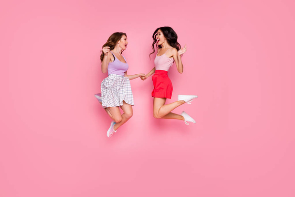 Full length body size view portrait of nice-looking attractive lovely careless carefree cheerful cheery girls having fun time jumping up in air campus isolated over pink pastel background - Foto, immagini