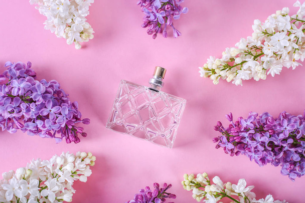 Parfümeri ve çiçek kokusu konsepti. Pembe arka planda llilac çiçekler ile merkezinde parfüm şişe. Yaratıcı trendy düz yatıyordu - Fotoğraf, Görsel