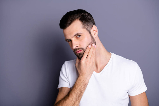 Close up photo amazing he him his macho perfect appearance touch arm hand neat bristle face calm not smiling ponder pensive look mirror bath shower wear casual white t-shirt isolated grey background - Foto, imagen