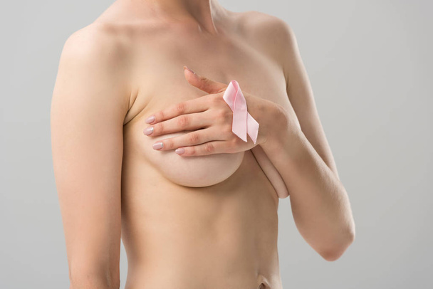 partial view of topless young woman with pink ribbon covering breast isolated on grey - Photo, Image