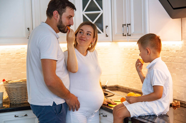 Boldog család. Várandós anya és a baba eszik és a smilingin a konyhában. - Fotó, kép