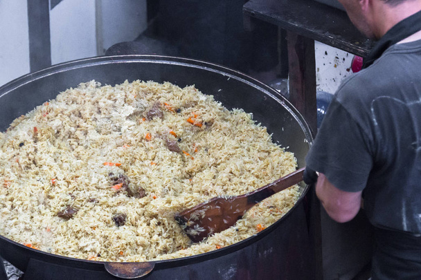 Appetizing dish. Eastern cuisine. Rice and meat pilaf for a big company. Cast-iron pan. Chan with food. Street Food Festival. A national dish. - Photo, Image