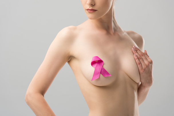 cropped view of naked young woman with pink ribbon isolated on grey - Photo, Image